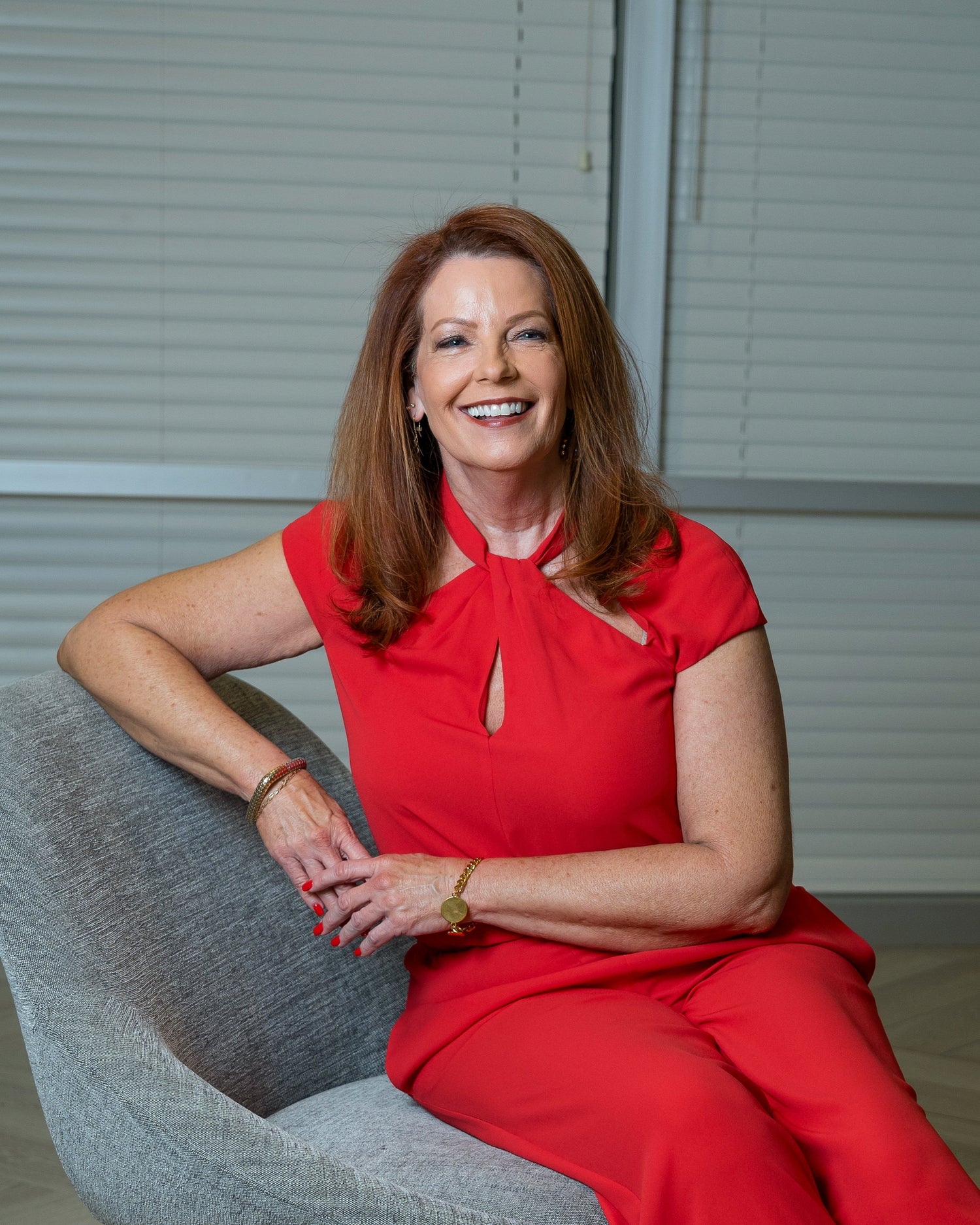 Woman in a red dress sitting on a gray chair in an office setting
